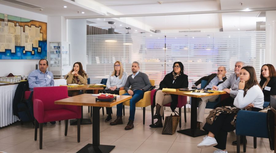 School teachers and principals attending a course on adult education sitting in a conference room listening to a lecture.