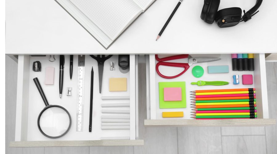 Office drawer neatly organized. Each item in its own compartment. Colourful office supplies such as paper, staples and felt tips.