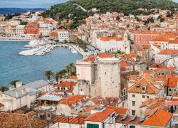 A view of red roofs and white stone houses next to the sea and port in Split Croatia with Marjan forest park overlooking the city, as seen from the bell tower of Saint Domnius cathedral. This photo is a link to Split Croatia location page.