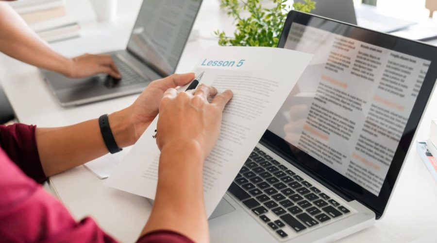 a teacher sitting at a laptop preparing a lesson plan using AI