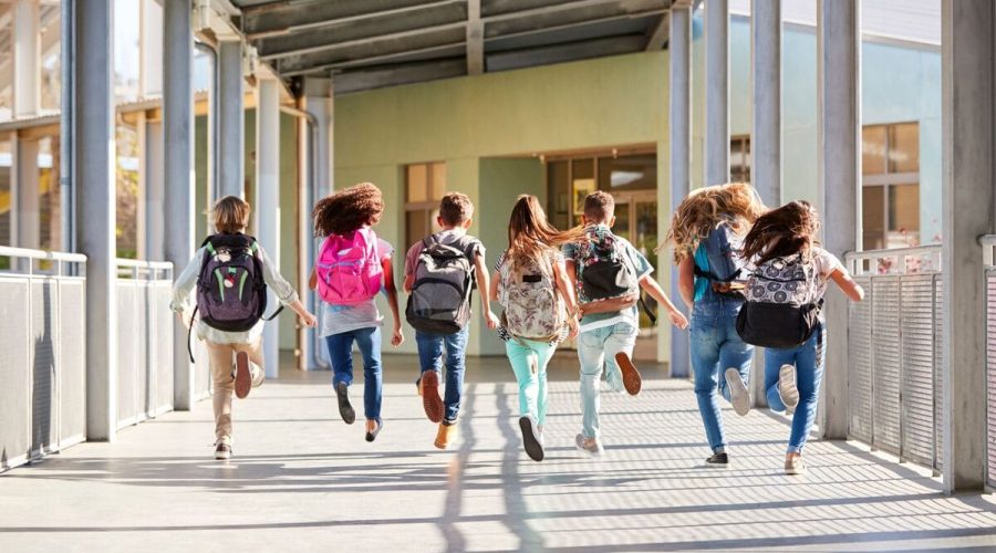 Students shown running with school bags on their back in the school hallway, a representation of school management course for principals and school leading staff course at Platform21