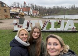 Agnese, Darta and Ana in front of the sign Latvia in Talsi, during Erasmus+ Invited Expert visit