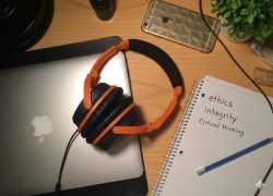 A student’s messy desk with a laptop, a notebook and headphones lying on the desk